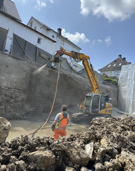 Mitarbeiter mit großem Bagger bei der Baugrubensicherung